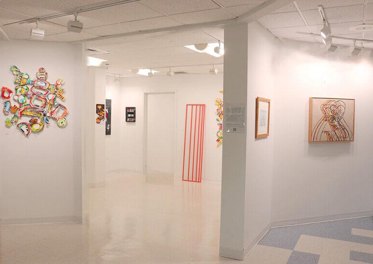 艺术画廊空间的广角视图，有几幅画和一个雕塑.